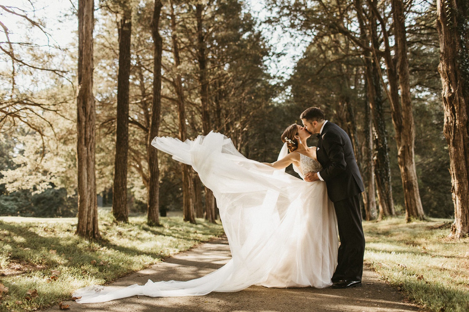 Couple kisses with flowing wedding dress in grove at poplar springs manor wedding