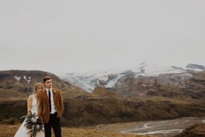 couple poses with iceland mountain behind them