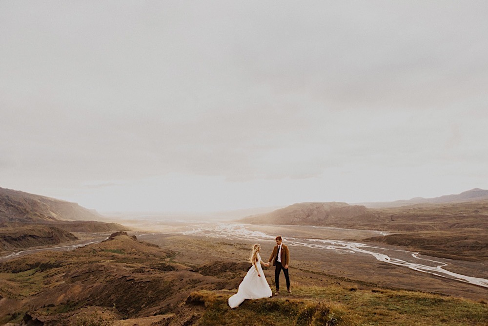 couple on icelandic mountain with sun and rivers in background