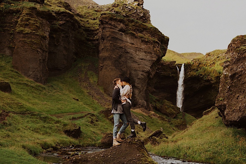 couple kiss in front of waterfall in iceland