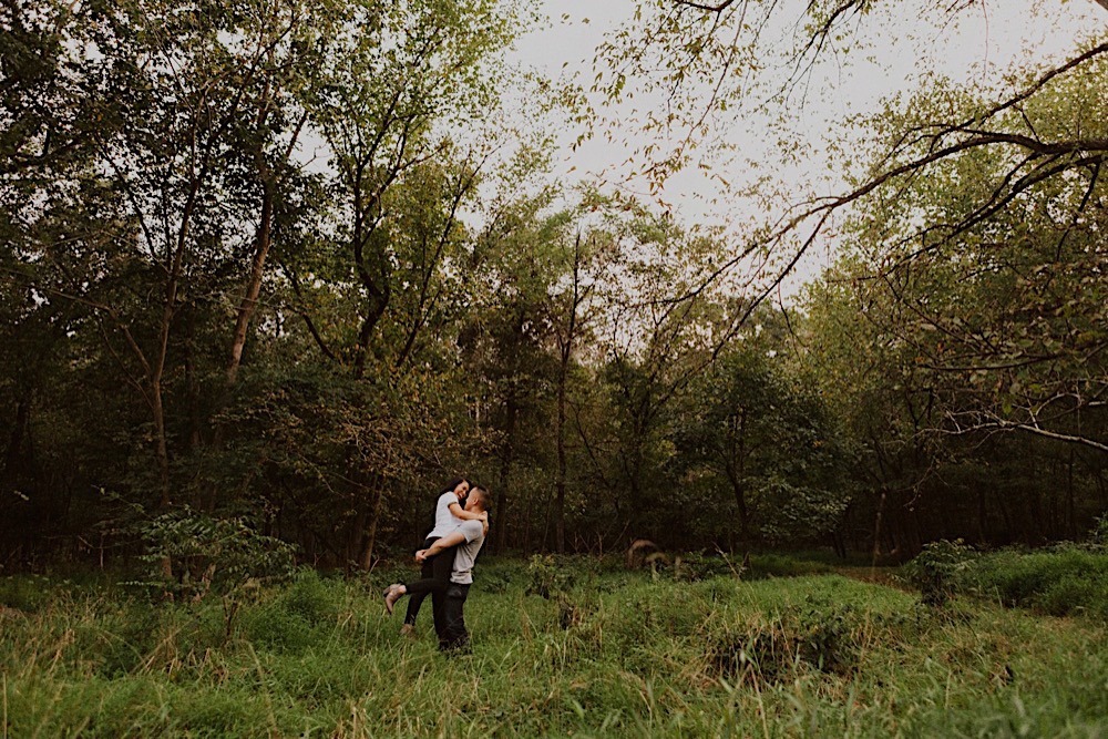 man picks-up fiance in field of tall grass