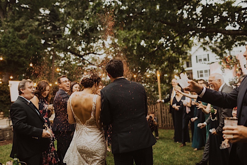 wedding guests throw confetti on bride and groom