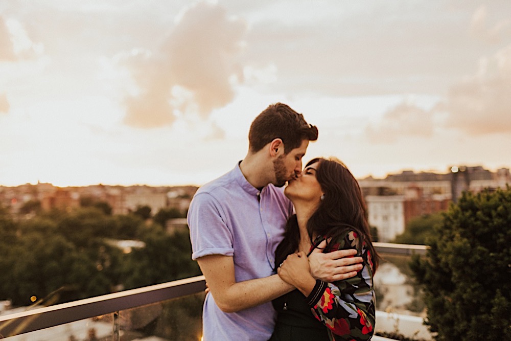 Engaged couple kiss during sunset on Washington DC rooftop