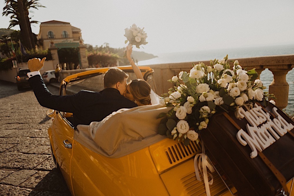 couple kisses in cute yellow vintage car in italy