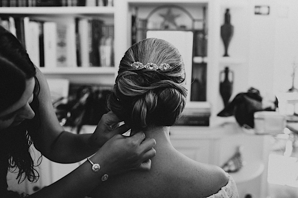 woman fixes brides hair before wedding