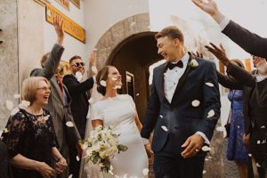 bride and groom laugh as guests throw petals on them