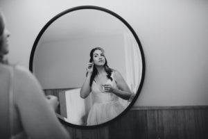 bride checks her earing in mirror