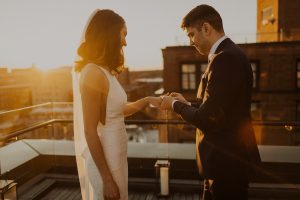 Couple exchange rings on the line rooftop at sunset