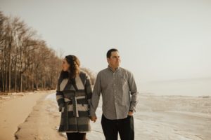 couple walks hand in hand on lake beach
