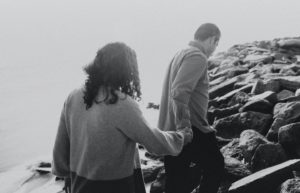 black and white portrait of couple walking along shore