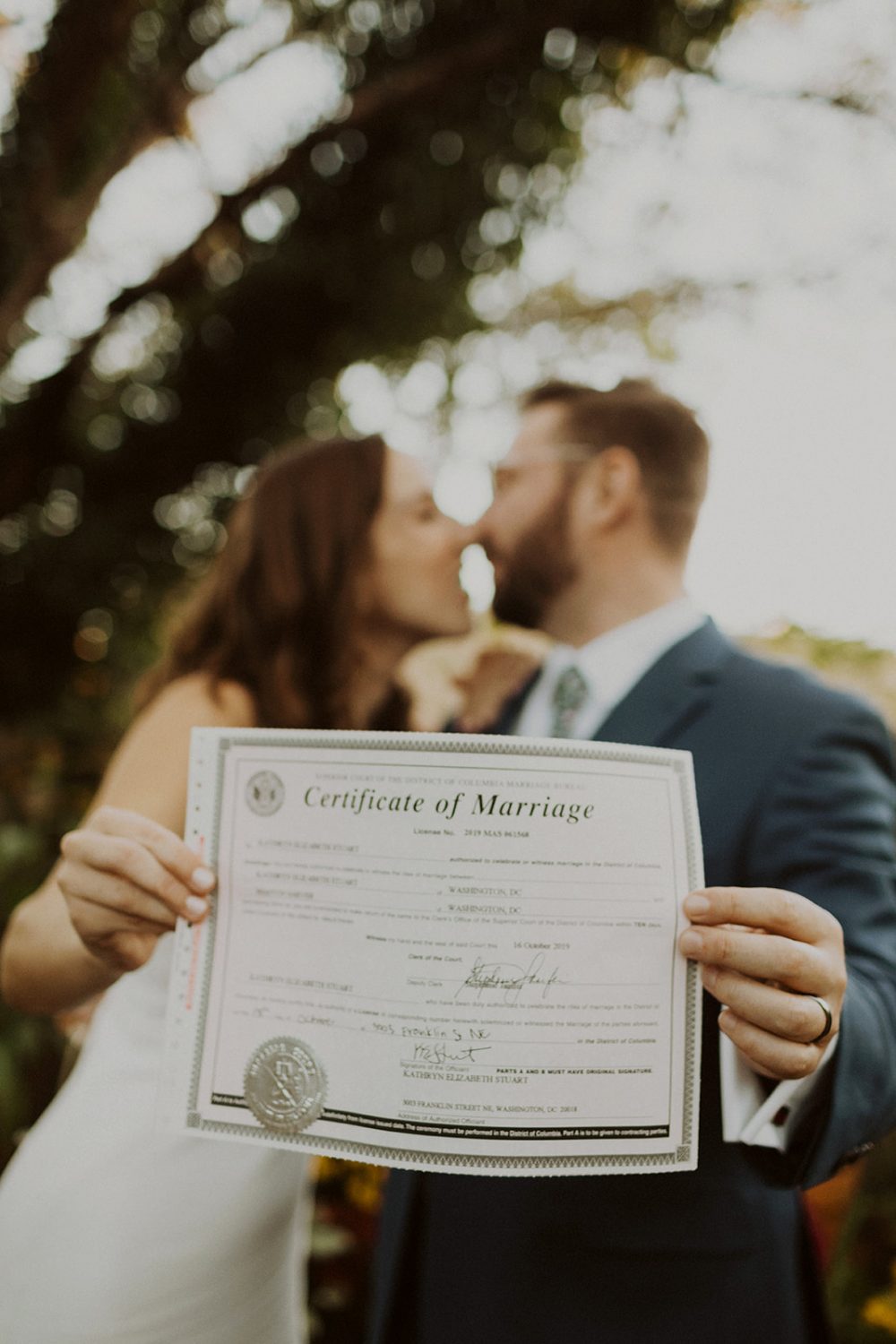 Bride and groom kiss holding marriage license at elopement