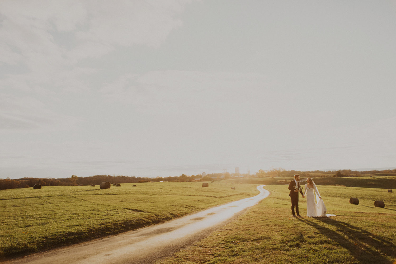 Couple walks through field at sunset at Goodstone Inn wedding