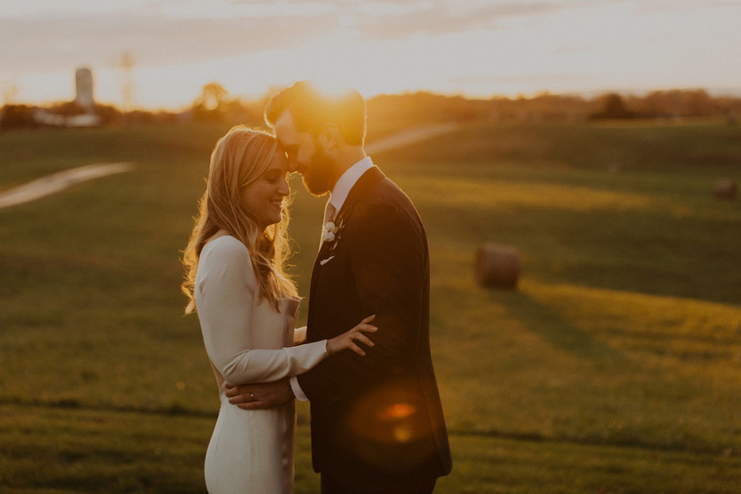 Couple embraces in field at sunset at Goodstone Inn 