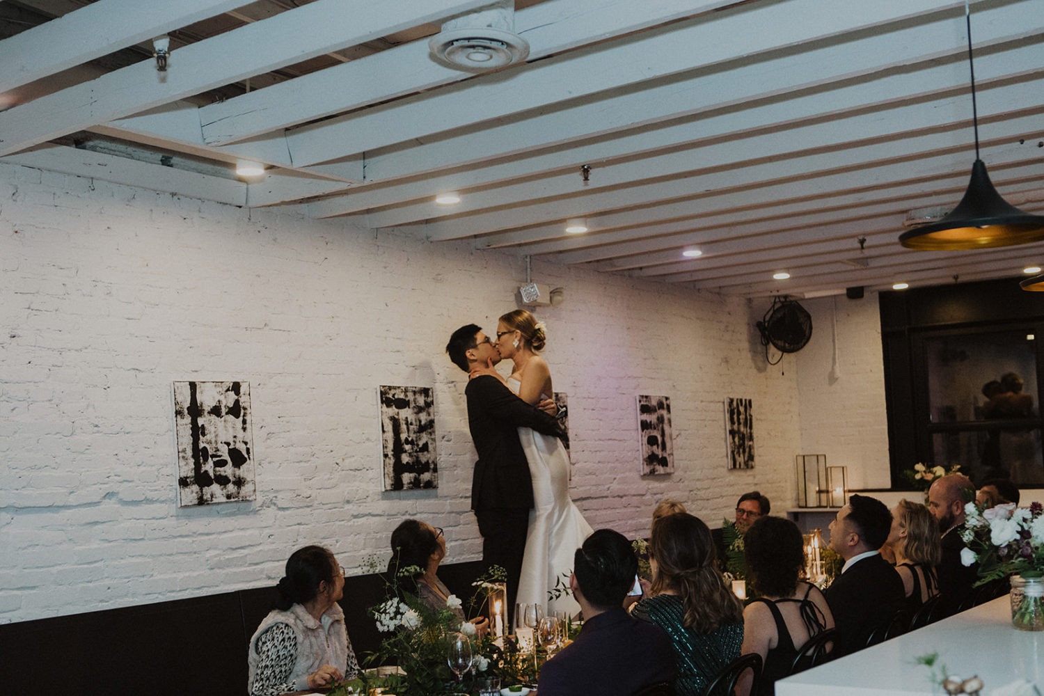 Couple kisses standing on reception table at intimate wedding