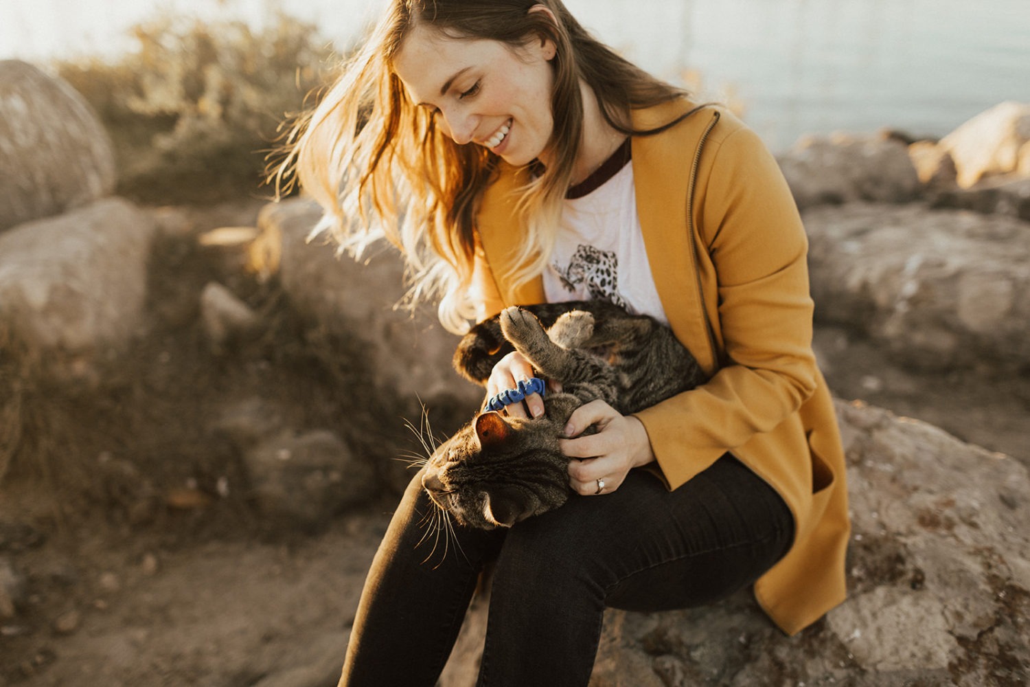 Woman holds her cat at sunset.