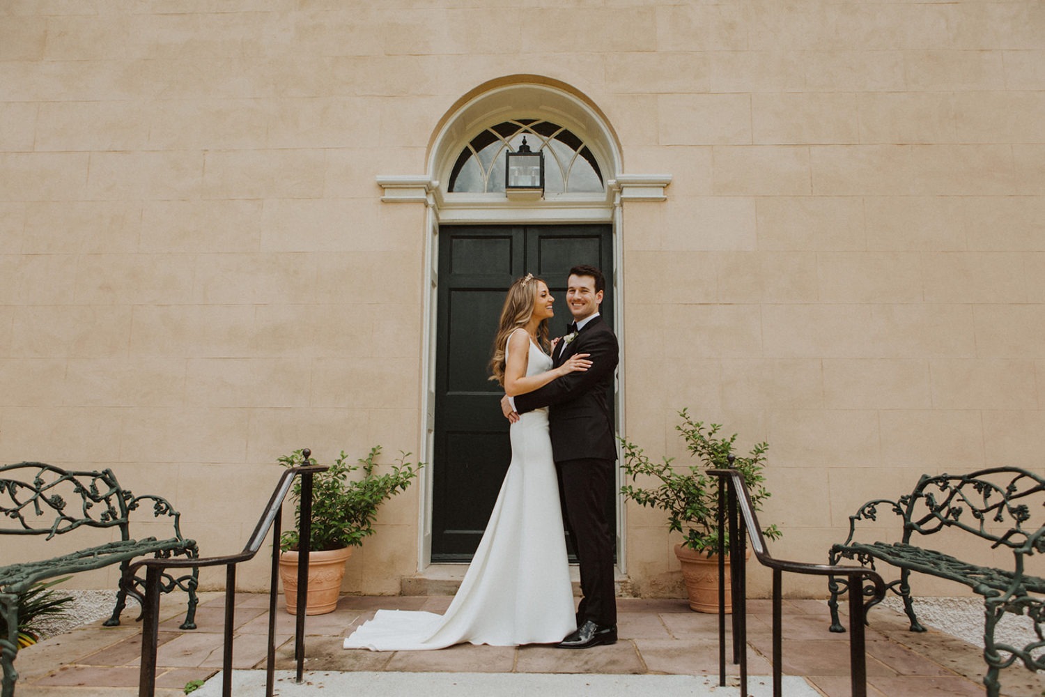 Couple embraces in front of wedding venue 
