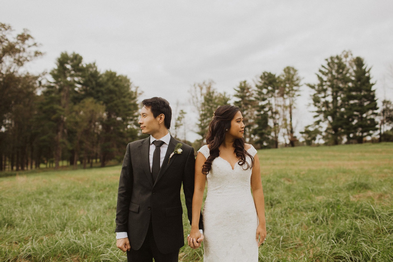 Couple stands holding hands in field at Virginia outdoor wedding venue.