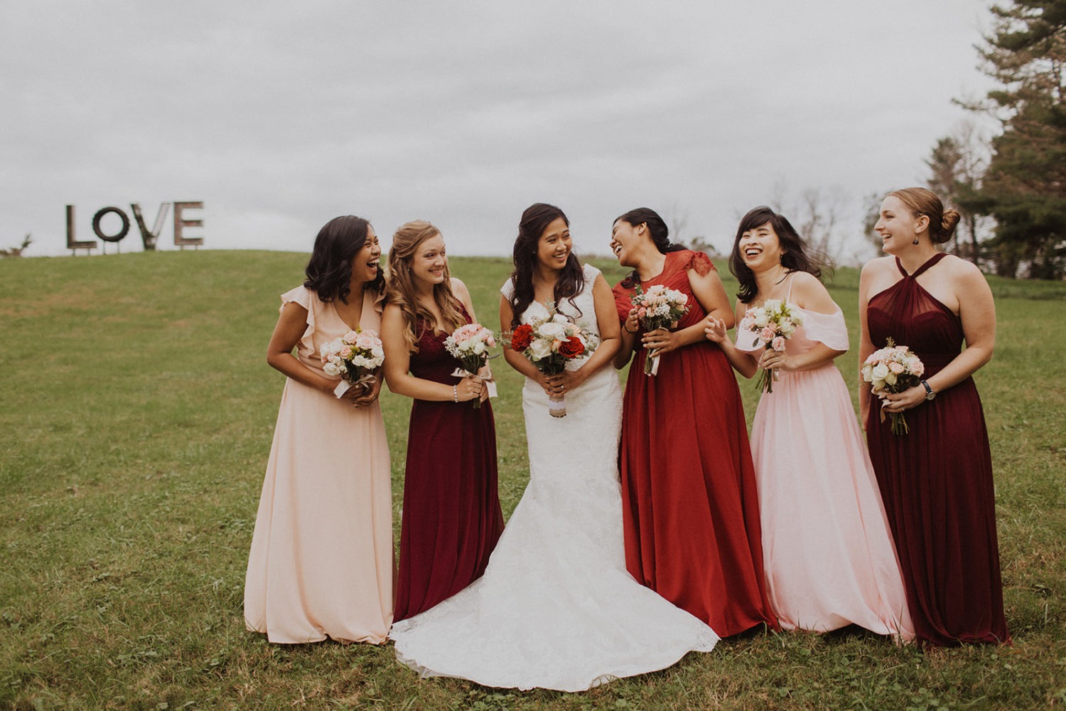 Bridesmaids stand in field with bride at Virginia outdoor wedding.