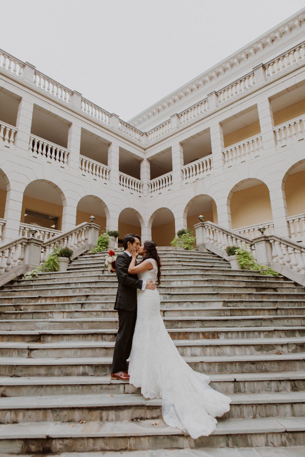 Couple stands on European-style staircase at outdoor Virginia wedding.