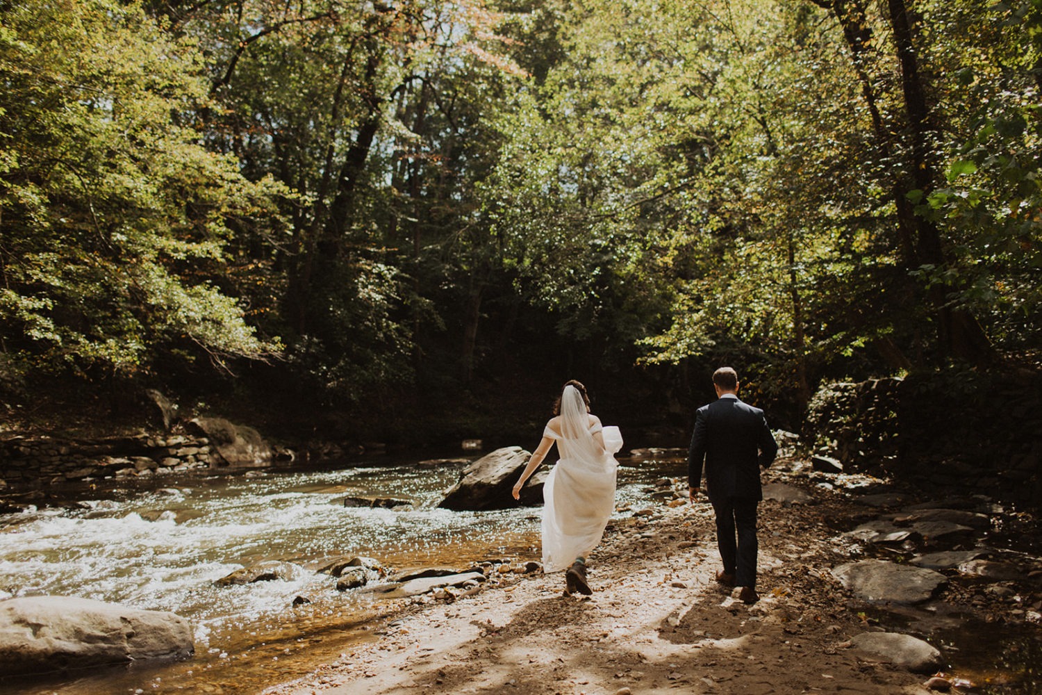 Couple walks along river at Rock Creek Park elopement