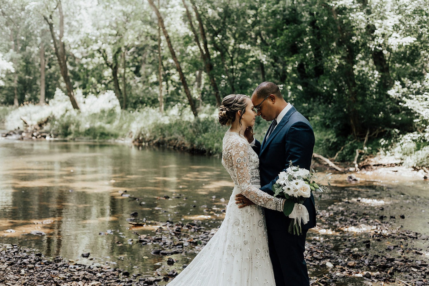 Couple embraces by Little Seneca Creek at their elopement
