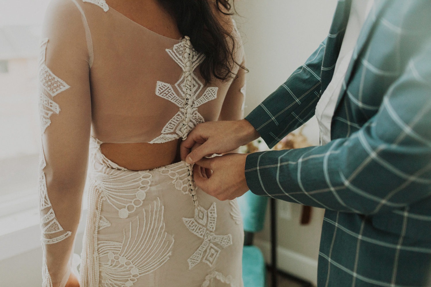 Groom buttons up bride's wedding dress at Oregon coast elopement