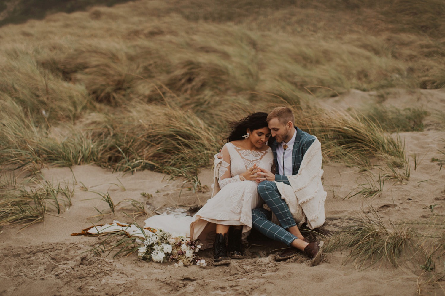 Couple sits on sand at Oregon coast elopement