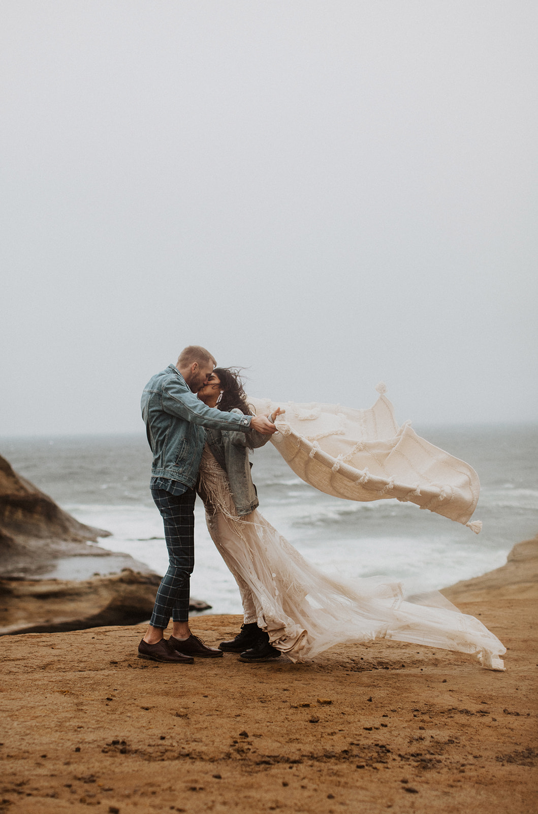 Couple kisses at windy oregon coast elopement