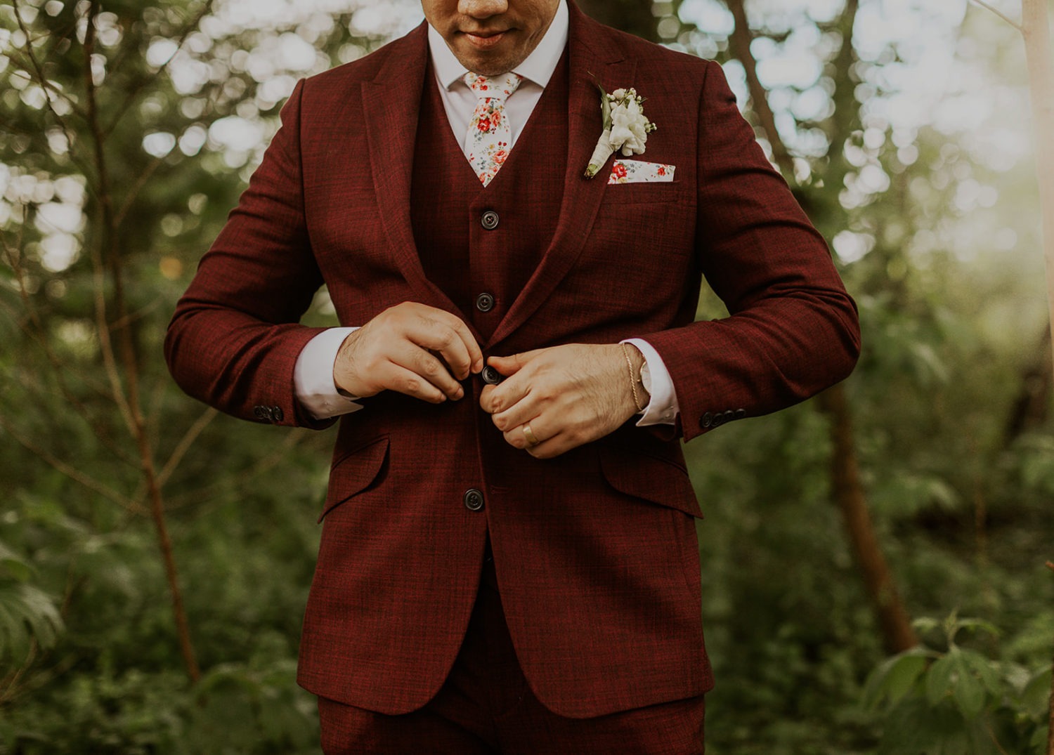 Groom buttons suit jacket at outdoor wedding