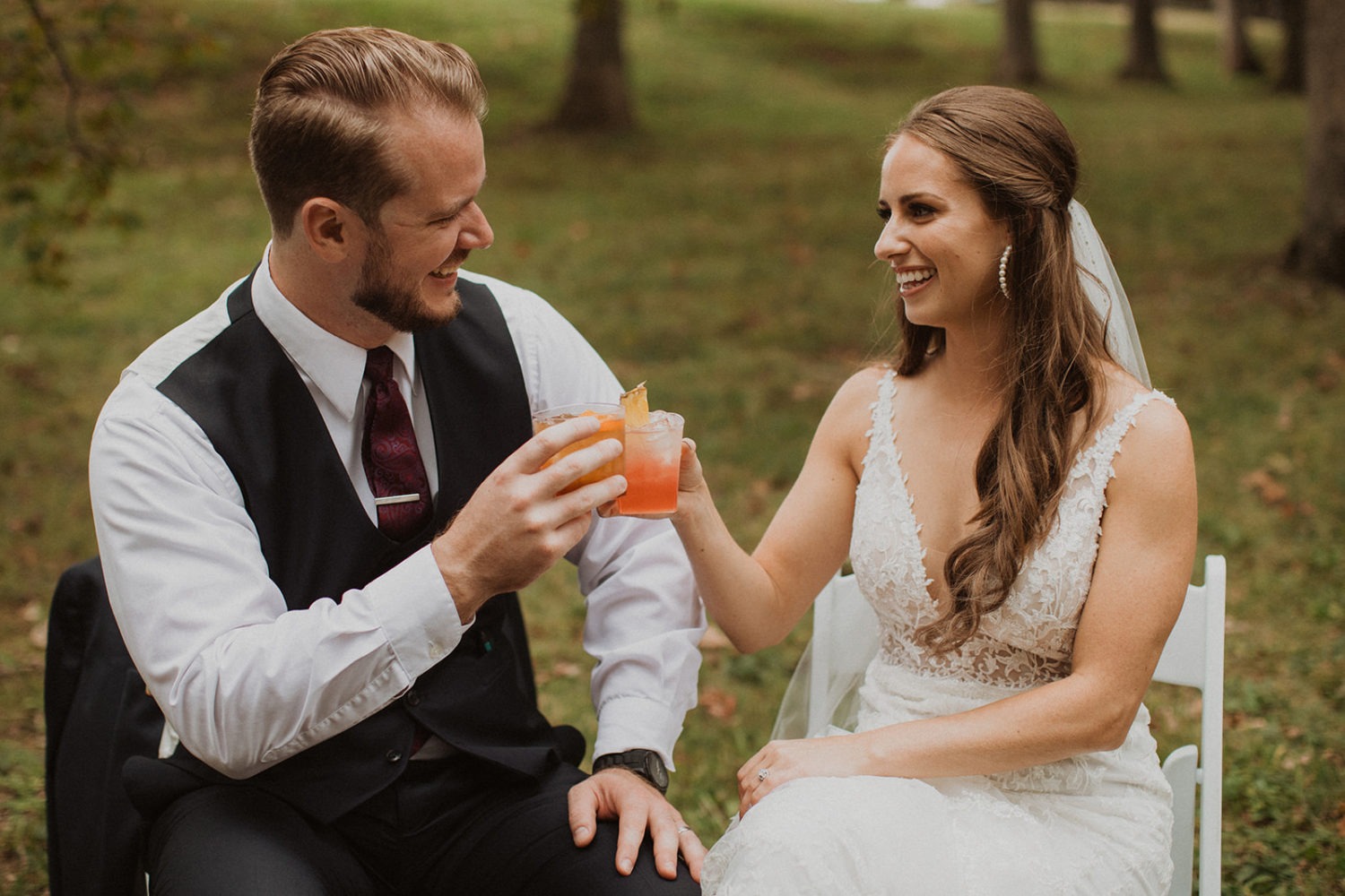 Couple cheers with cocktails at outdoor wedding