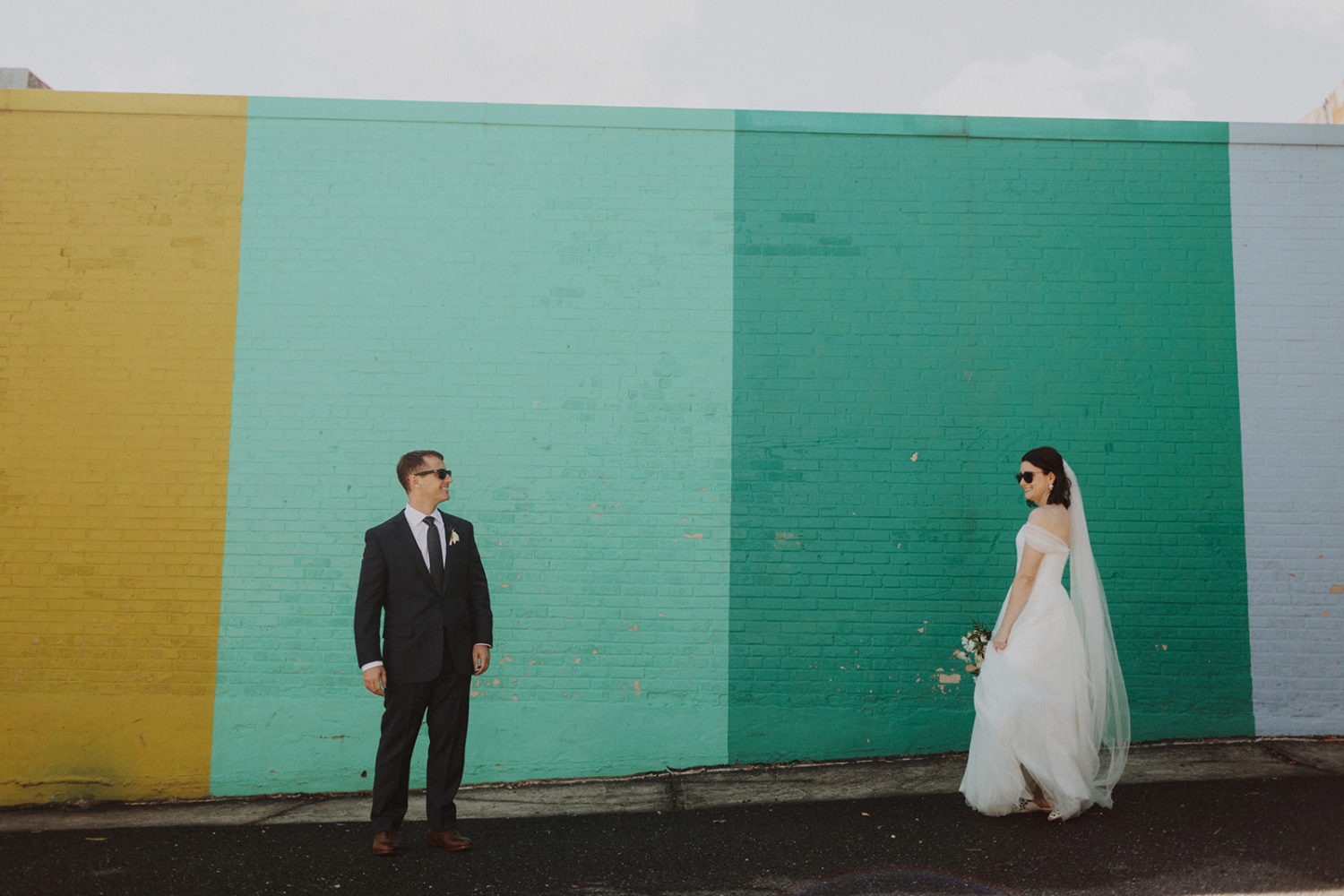 Couple stands in front of rainbow wall at full-day elopement