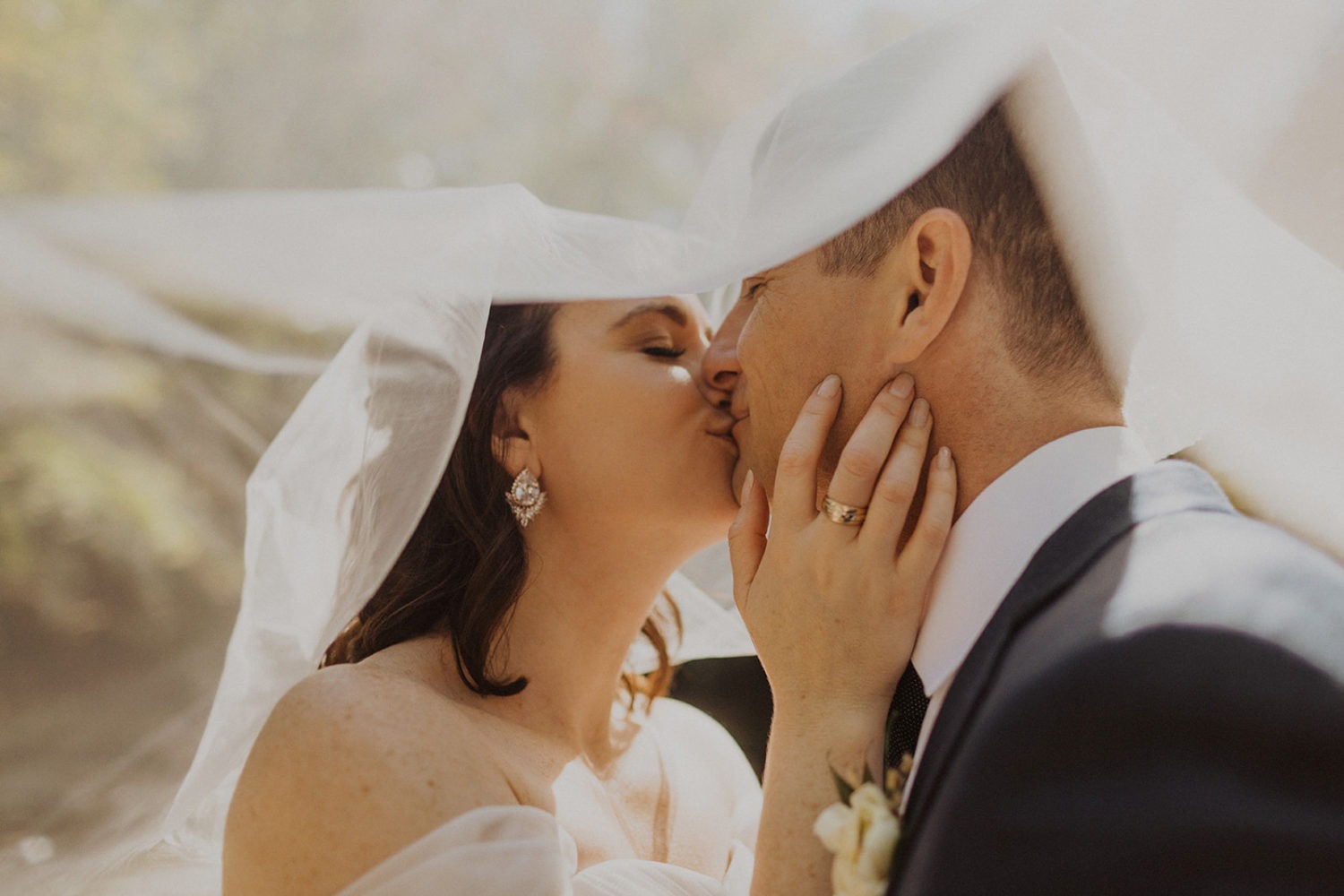 Couple kisses under veil at full-day elopement