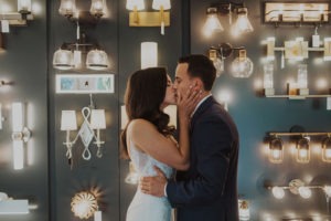 Couple kisses in light store at wedding first look