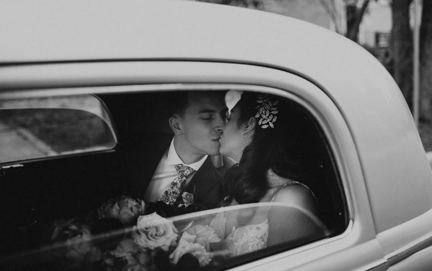 Couple kisses in vintage car at postponed wedding day
