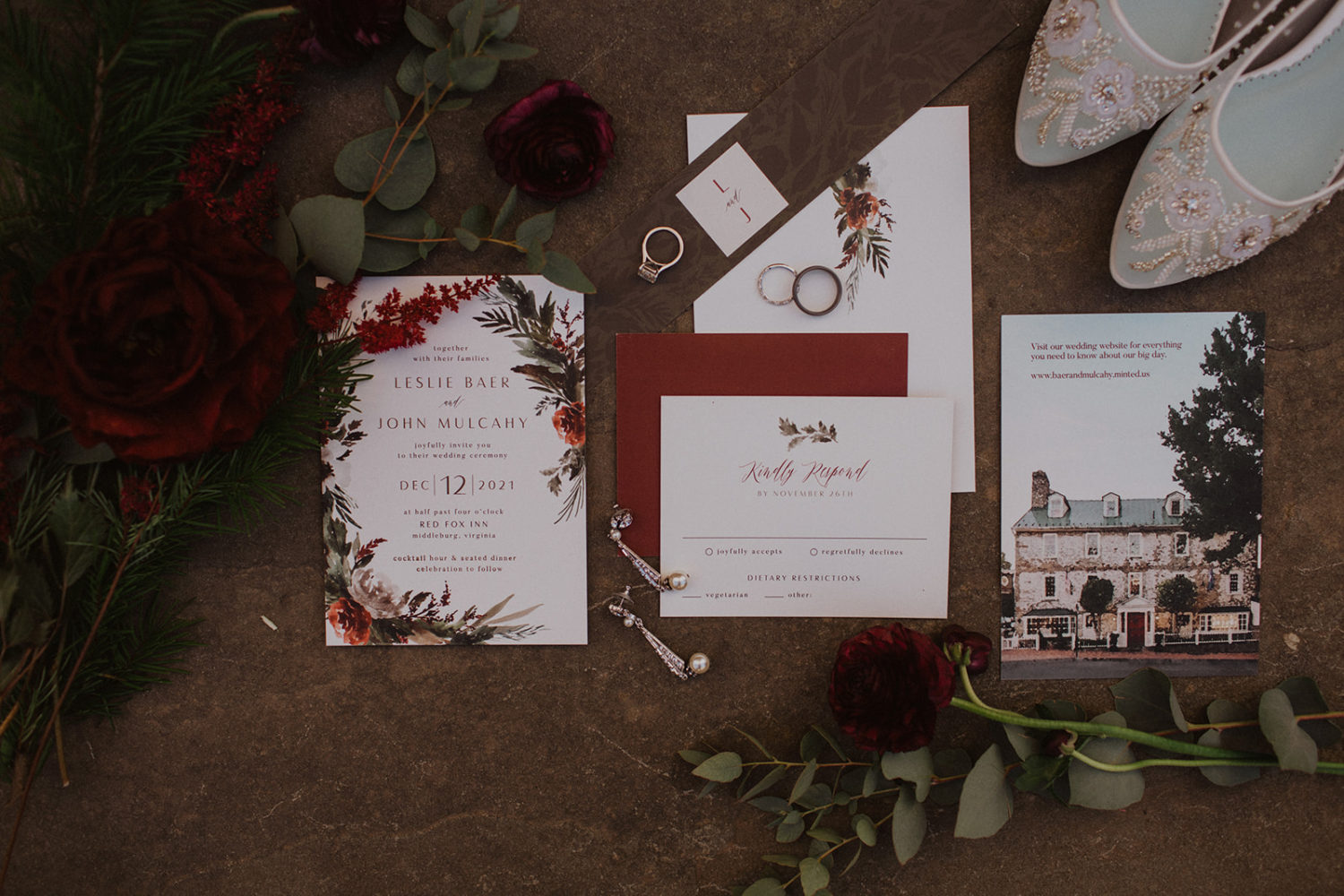 Flat lay of wedding invitation, rings, and accessories at festive winter wedding