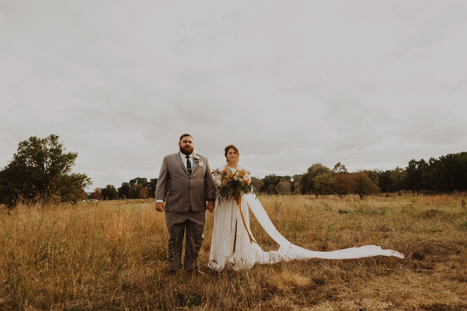 Couple holds hands in field at Arboretum garden wedding