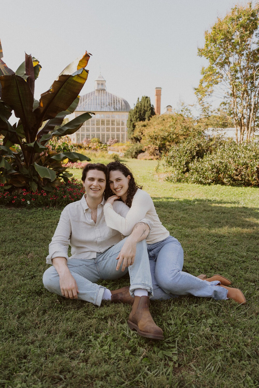 couple sit in the grass in front of the Rawlings Conservatory