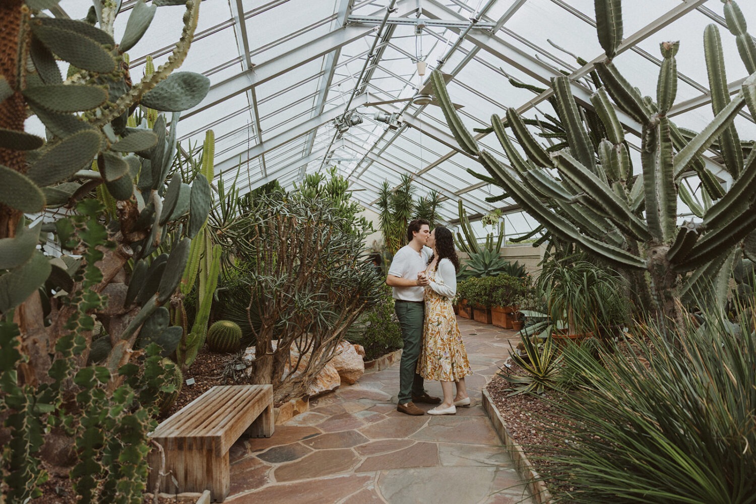 couple kiss along the pathway of the greenhouse