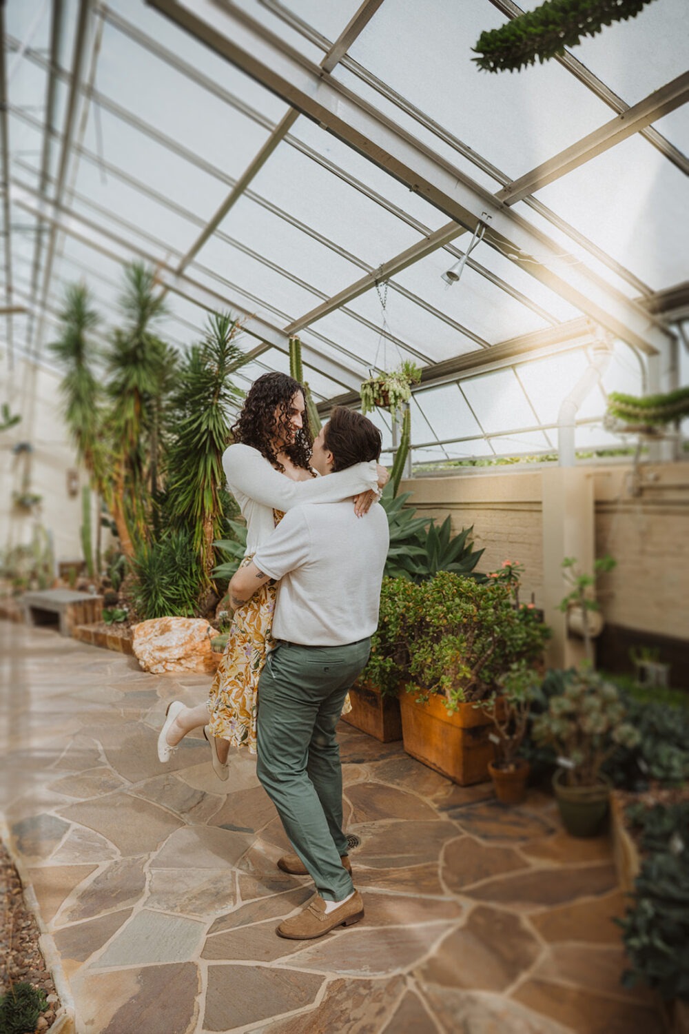 couple embrace in the middle of greenhouse
