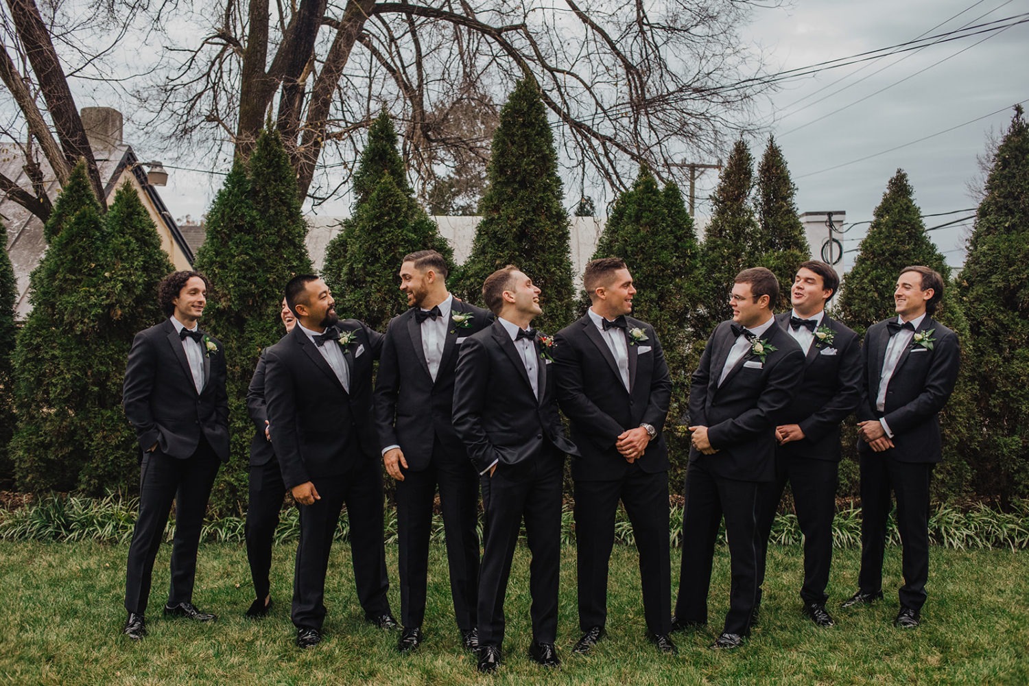 Groom laughs with groomsmen at velvet winter wedding