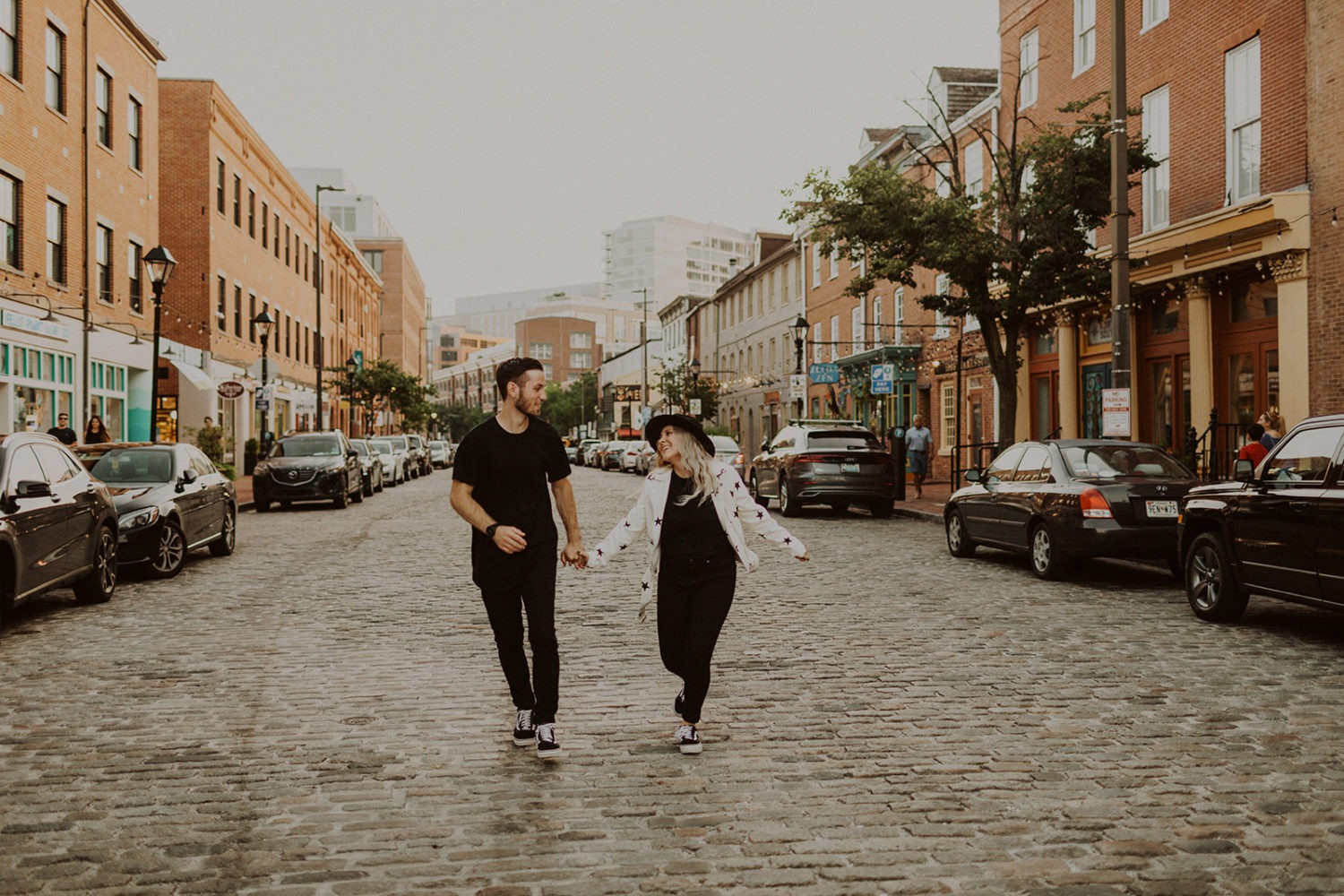 Couple runs holding hands in street at Baltimore engagement session