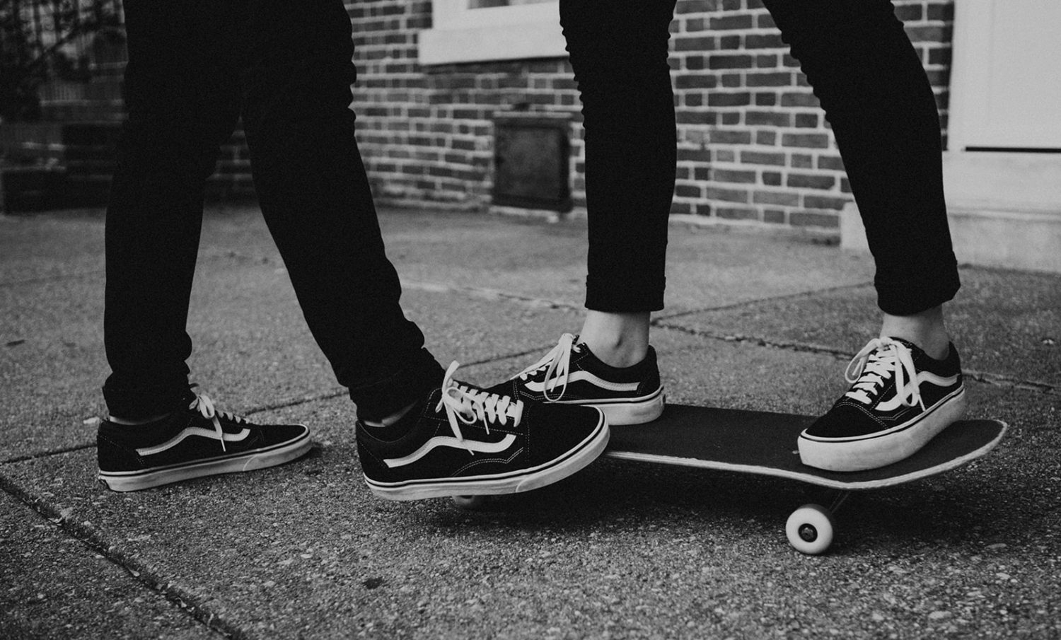 Couple stands on black skateboard together at Baltimore engagement session