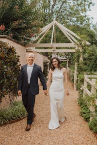 Couple walks holding hands in garden at red fox inn wedding