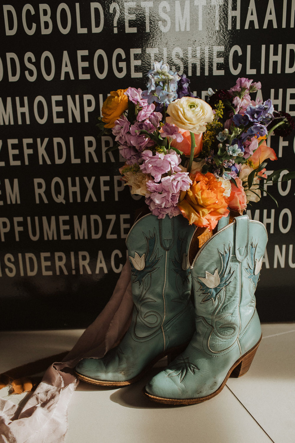 Bouquet of flowers placed in cowgirl boots during wedding morning getting ready