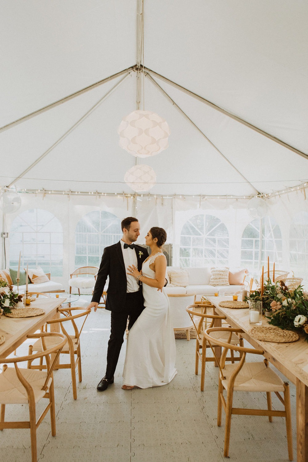 Couple stands in tented reception at backyard wedding