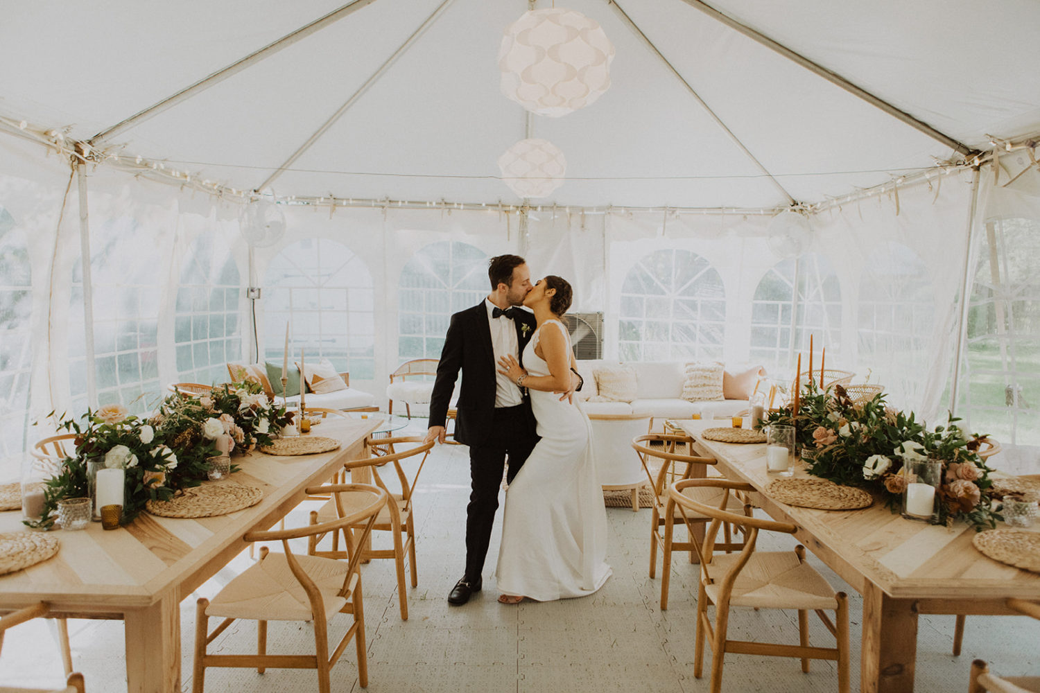 Couple kisses in reception tent at backyard wedding