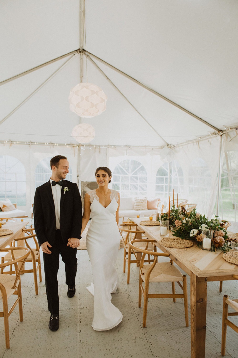 Couple walks along tented reception at backyard wedding