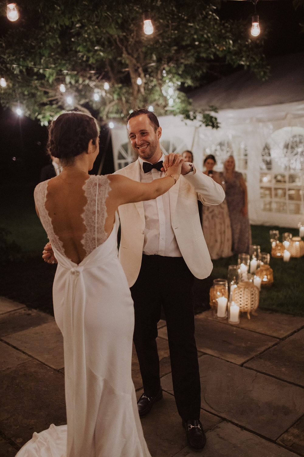 Couple dances at backyard wedding lit by twinkle lights and candles