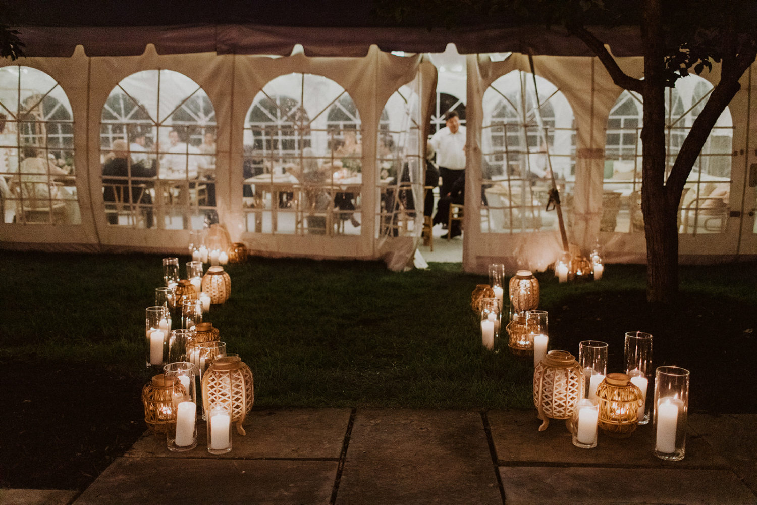 Reception tent lit by candles in vases at backyard wedding