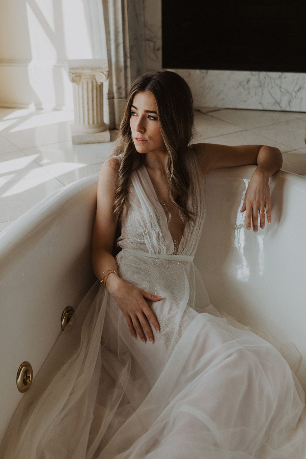 Bride sits in bathtub while getting ready on the wedding morning 
